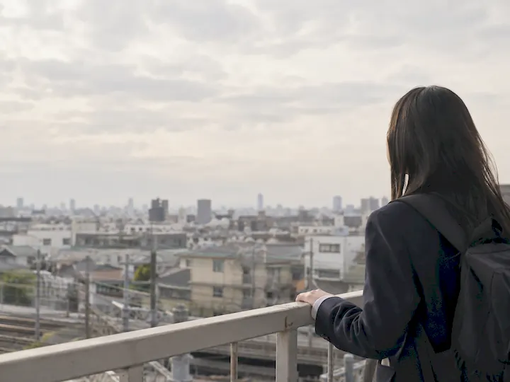 街を見渡す場所で、リュックを背負った高校生が景色を眺めている（イメージ）